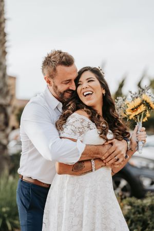 A joyful embrace outdoors with sunflower bouquet and natural lighting.
