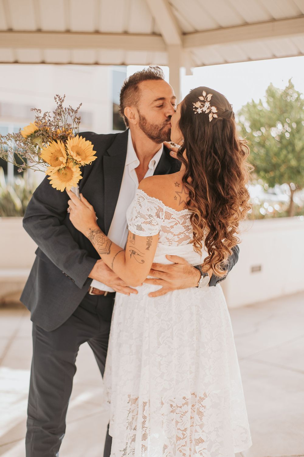 A romantic wedding moment with sunflowers and a lace dress under a white gazebo.