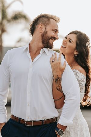 A romantic couple shares joyful laughter while dressed in wedding attire during a golden hour photoshoot.