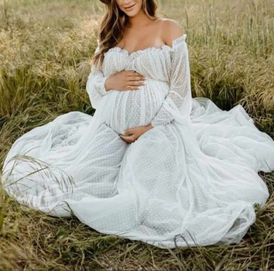 Ethereal maternity photo featuring a white lace dress in a sunlit meadow.