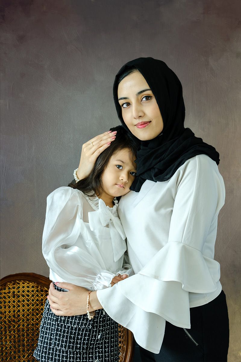 Beautiful mother holds daughter to her chest during photoshoot in Queens photo Studio.