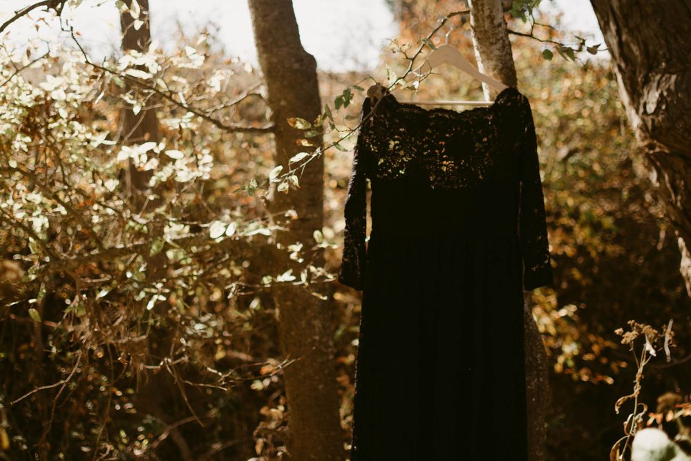 A black vintage dress hangs mysteriously among autumn trees and falling leaves.