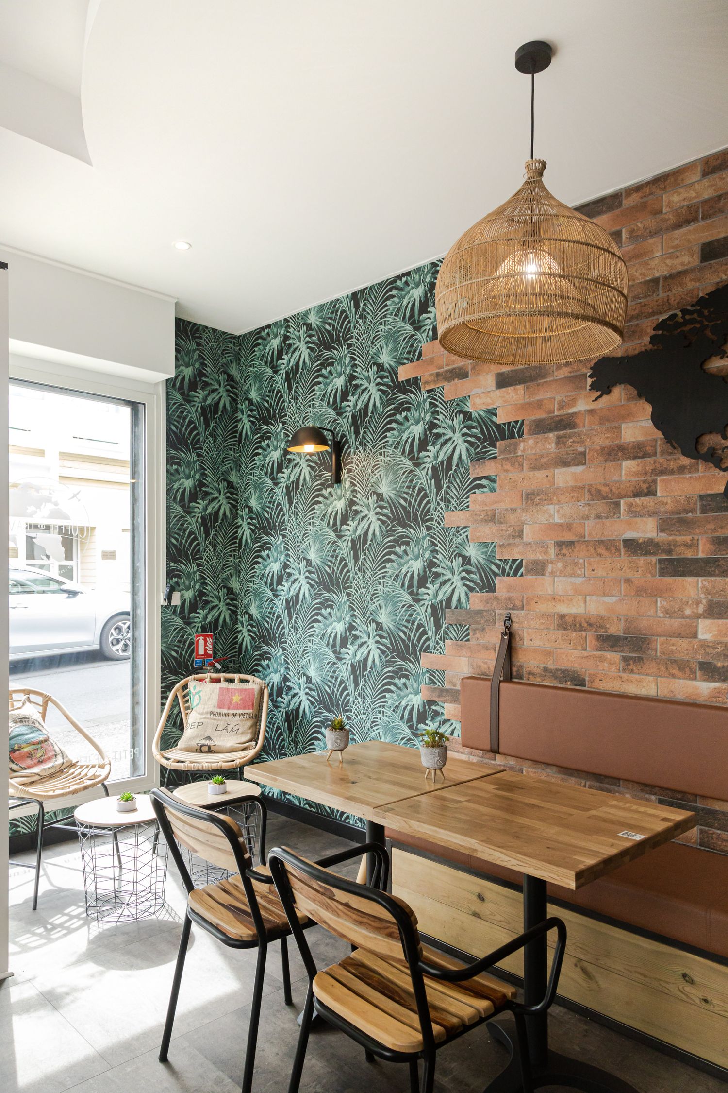 Modern cafe interior with wooden tables and tropical wallpaper design.