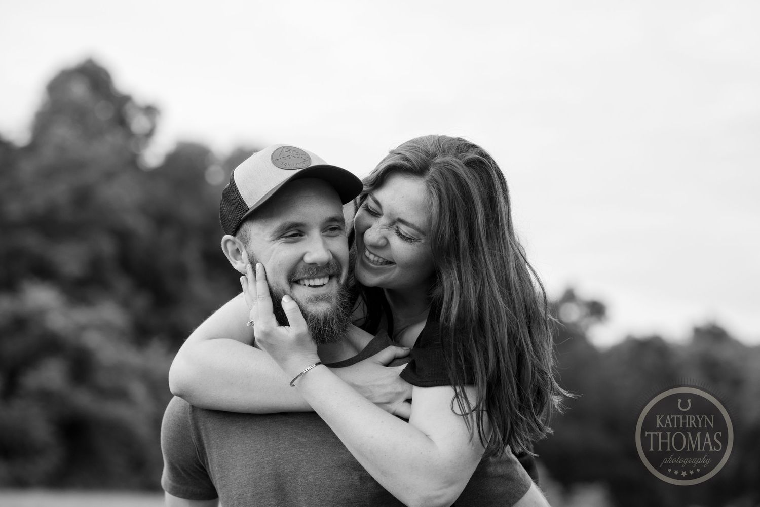 Happy couple embracing and laughing in a black and white outdoor portrait.