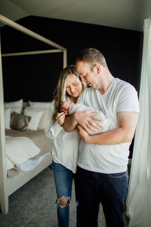 Intimate couple embracing and laughing together in a bright bedroom setting.