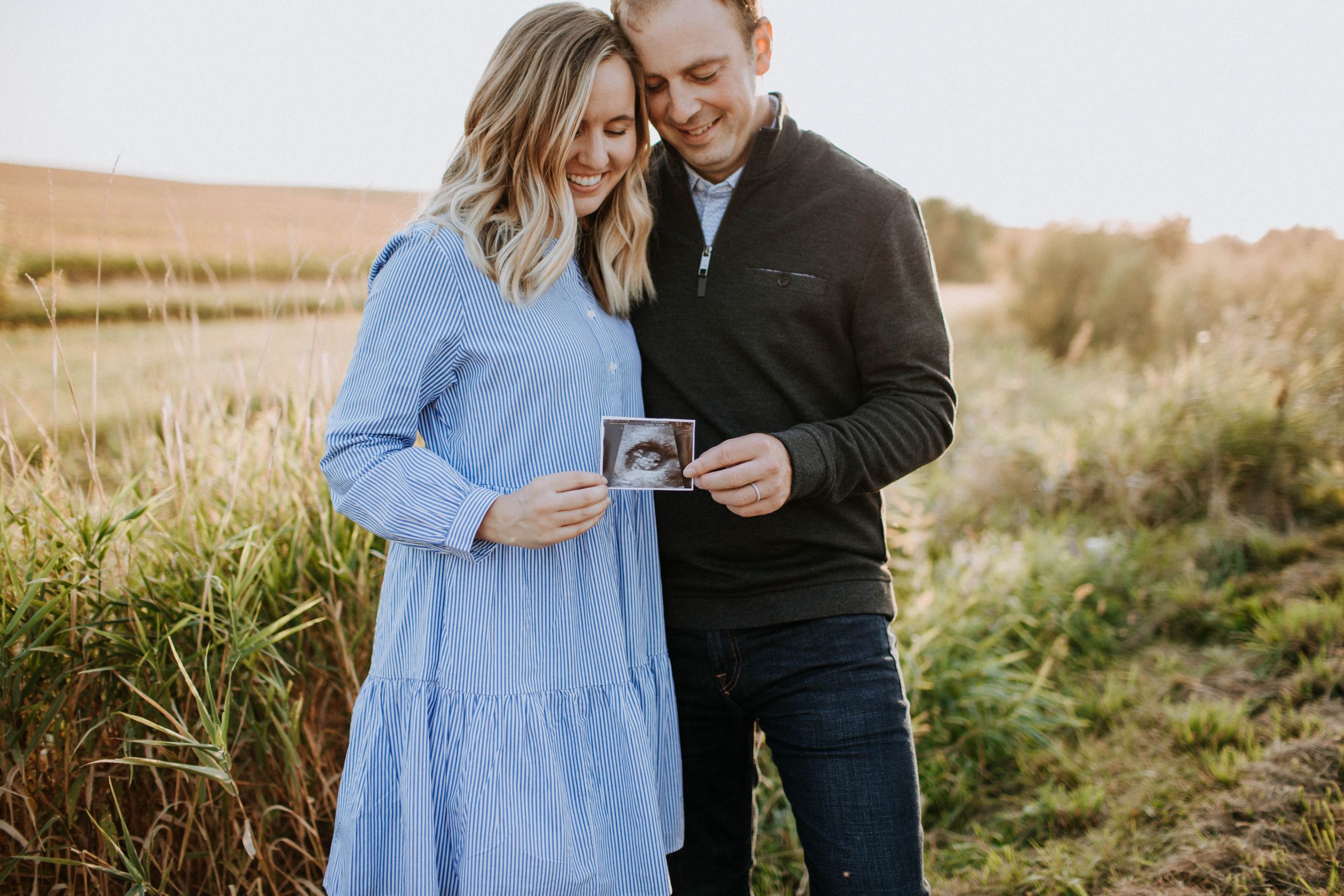 Couple sharing tender moments in a field during golden hour.