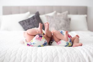 Baby feet with colorful floral socks resting on white bedding.