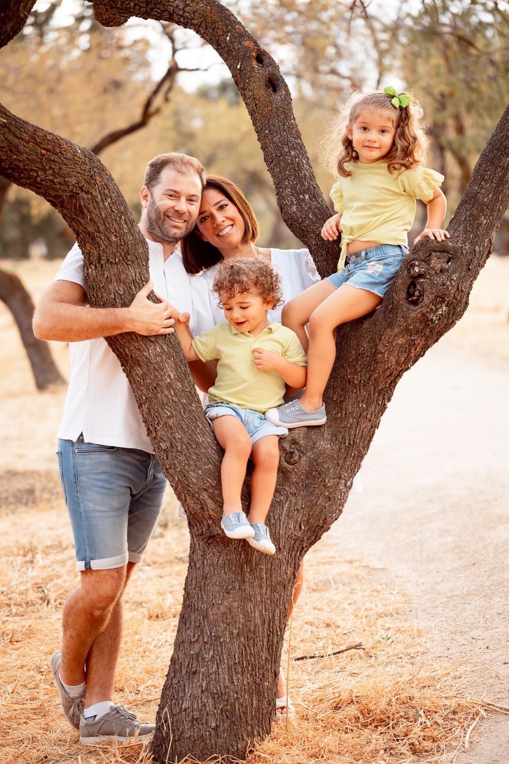 Family having fun around a large tree trunk in a natural outdoor setting.