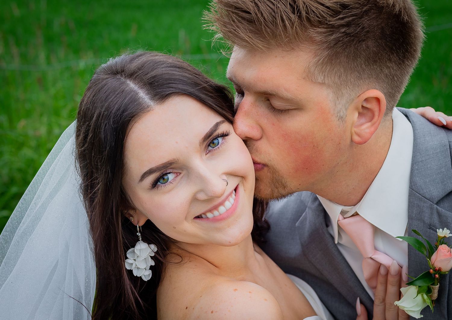 Romantic wedding moment captured in lush green outdoor setting.