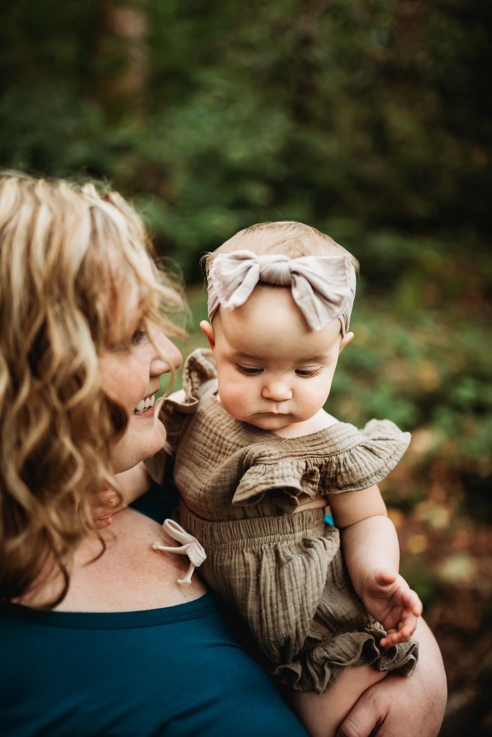 Mother lovingly looks at daughter while holding her in outdoor photography session in Asheville, NC