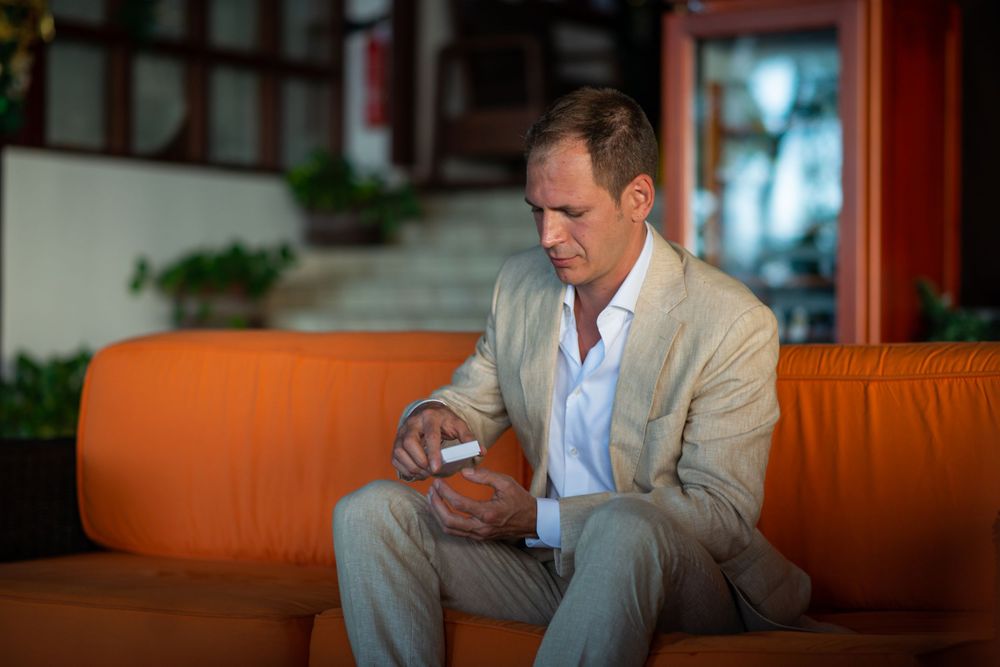 Candid portrait of man in light suit sitting in warm-lit indoor setting.