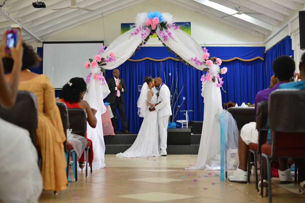 Wedding ceremony setup in indoor venue with blue curtains and pink decorations.