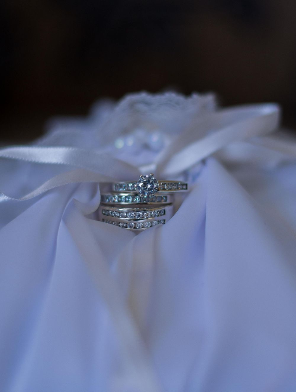 Close-up details of elegant diamond wedding rings resting on white fabric.