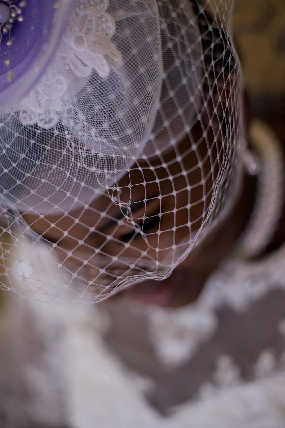 Delicate white bridal veil with intricate lace pattern details shown in close-up.