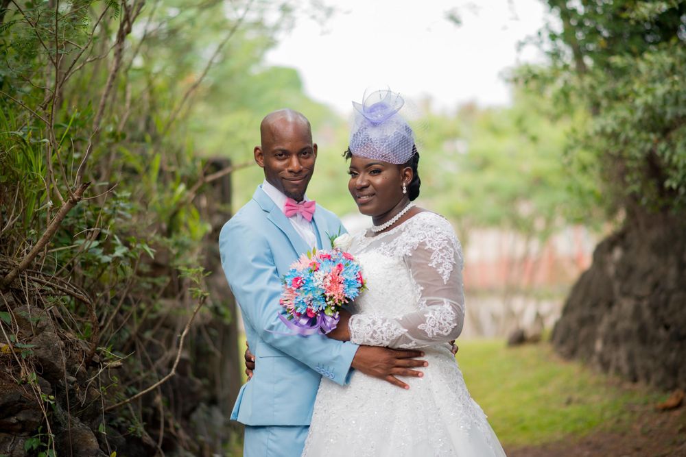Wedding couple in light blue suit and white dress pose together in a garden setting.