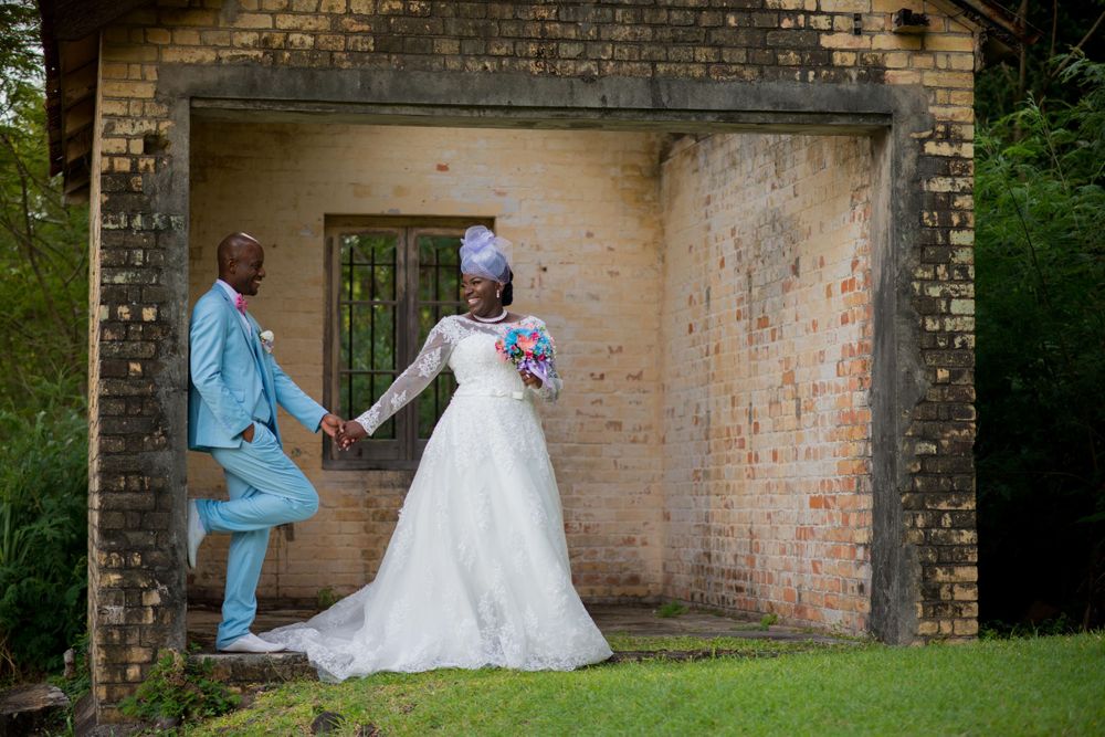 Wedding couple poses against rustic brick wall backdrop in formal attire.