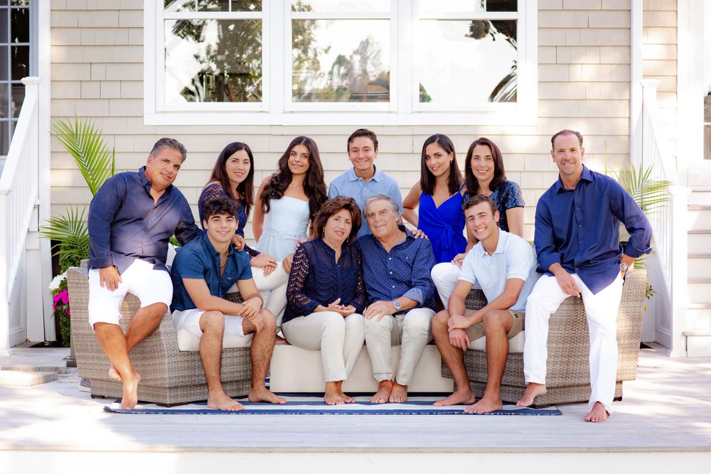 Extended family portrait on white porch steps wearing coordinated blue and white outfits.