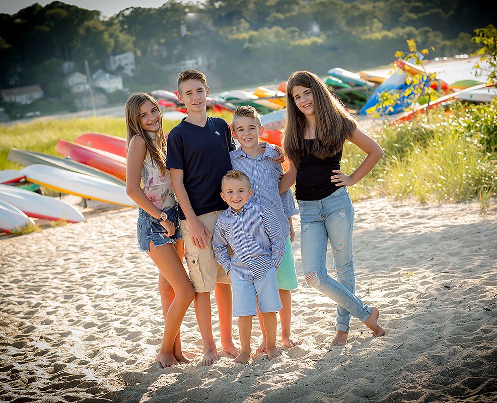 Group photo of family members standing together on a beach with kayaks in background.