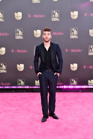Stylish guest in navy suit poses on pink carpet at industry event.