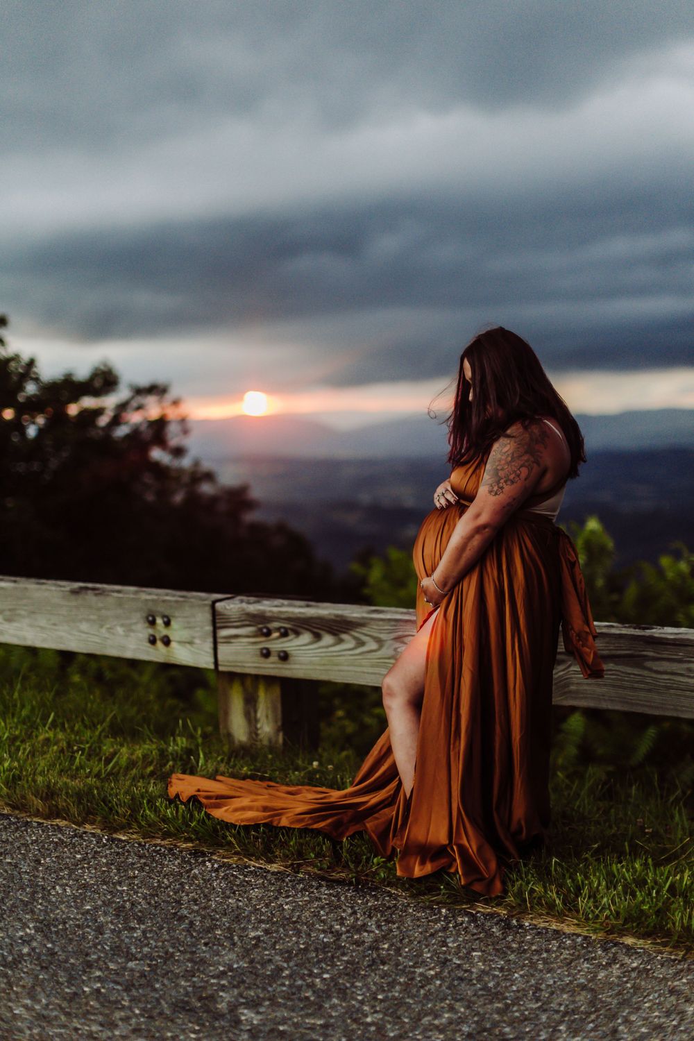 A flowing rust-colored dress catches the sunset light as a figure stands against a mountain overlook.