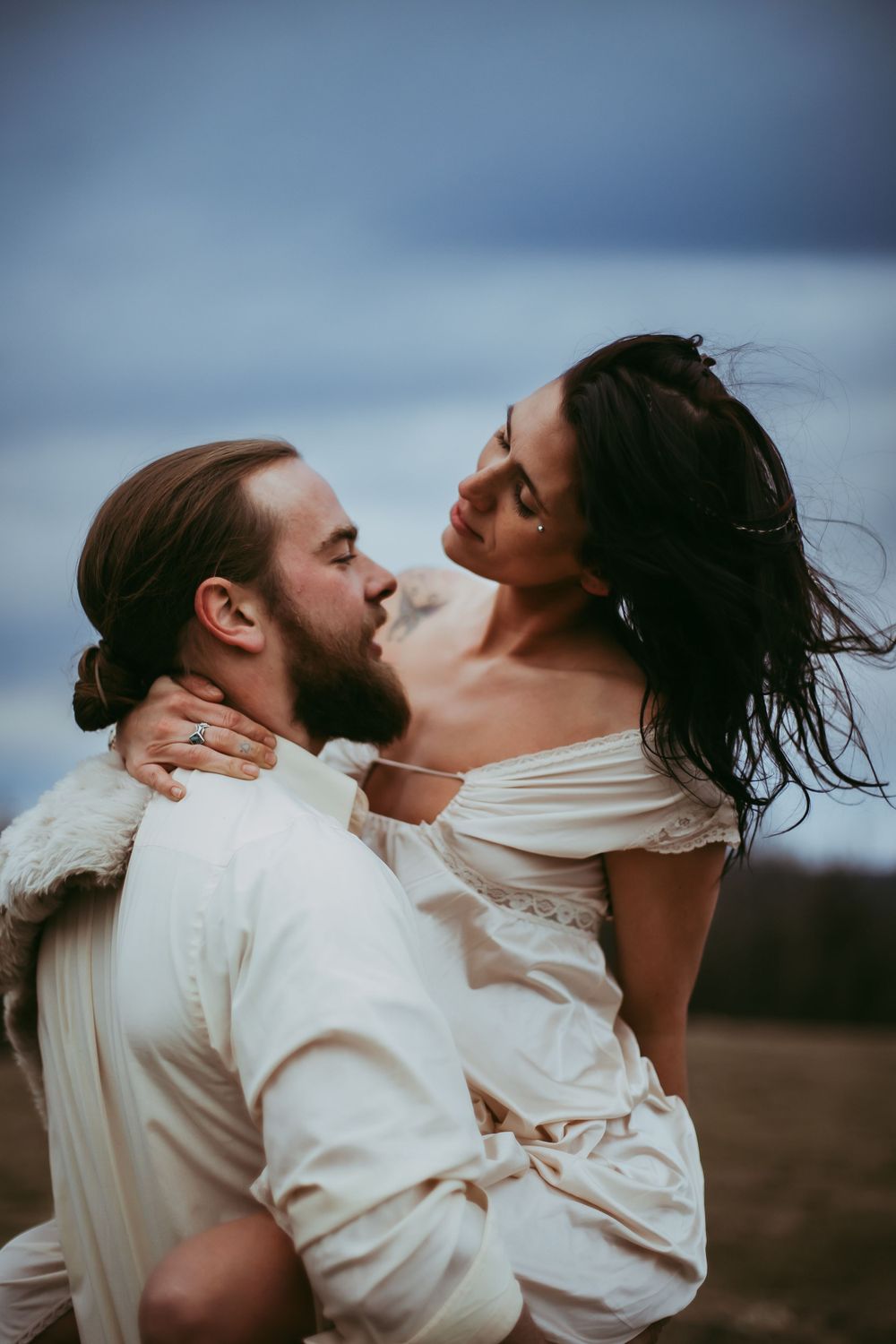 A romantic portrait of a couple sharing an intimate moment against a dusky sky.