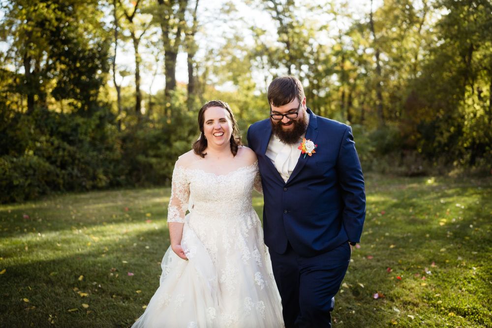 Couple walking together on green grass during an autumn outdoor photoshoot.