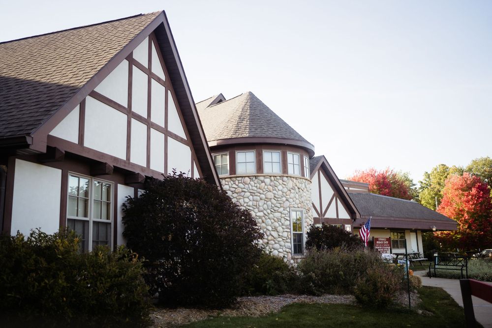 Tudor-style stone and white building with autumn foliage in background.