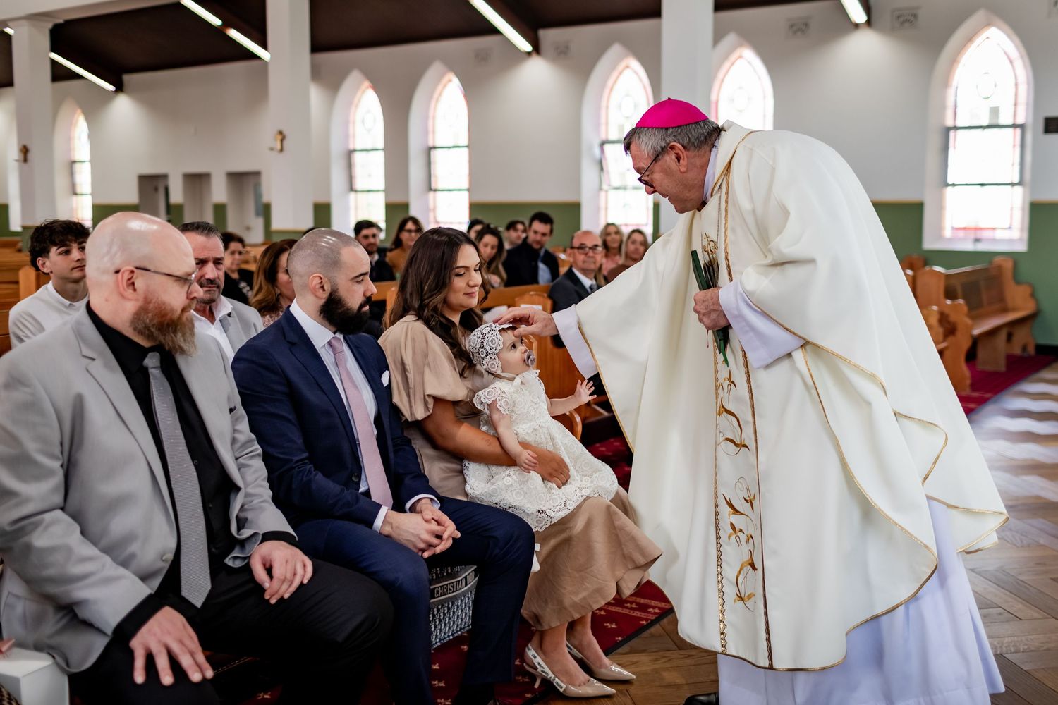 A religious ceremony taking place in a church with arched windows and wooden beams.
