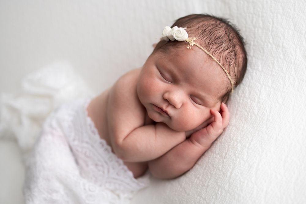Newborn baby girl on white blanket close up of her cute face.