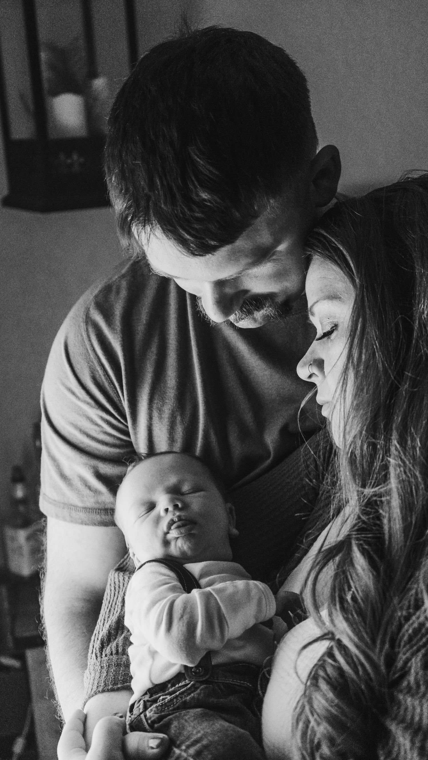 Black and white intimate photos of parents bonding with their newborn baby.