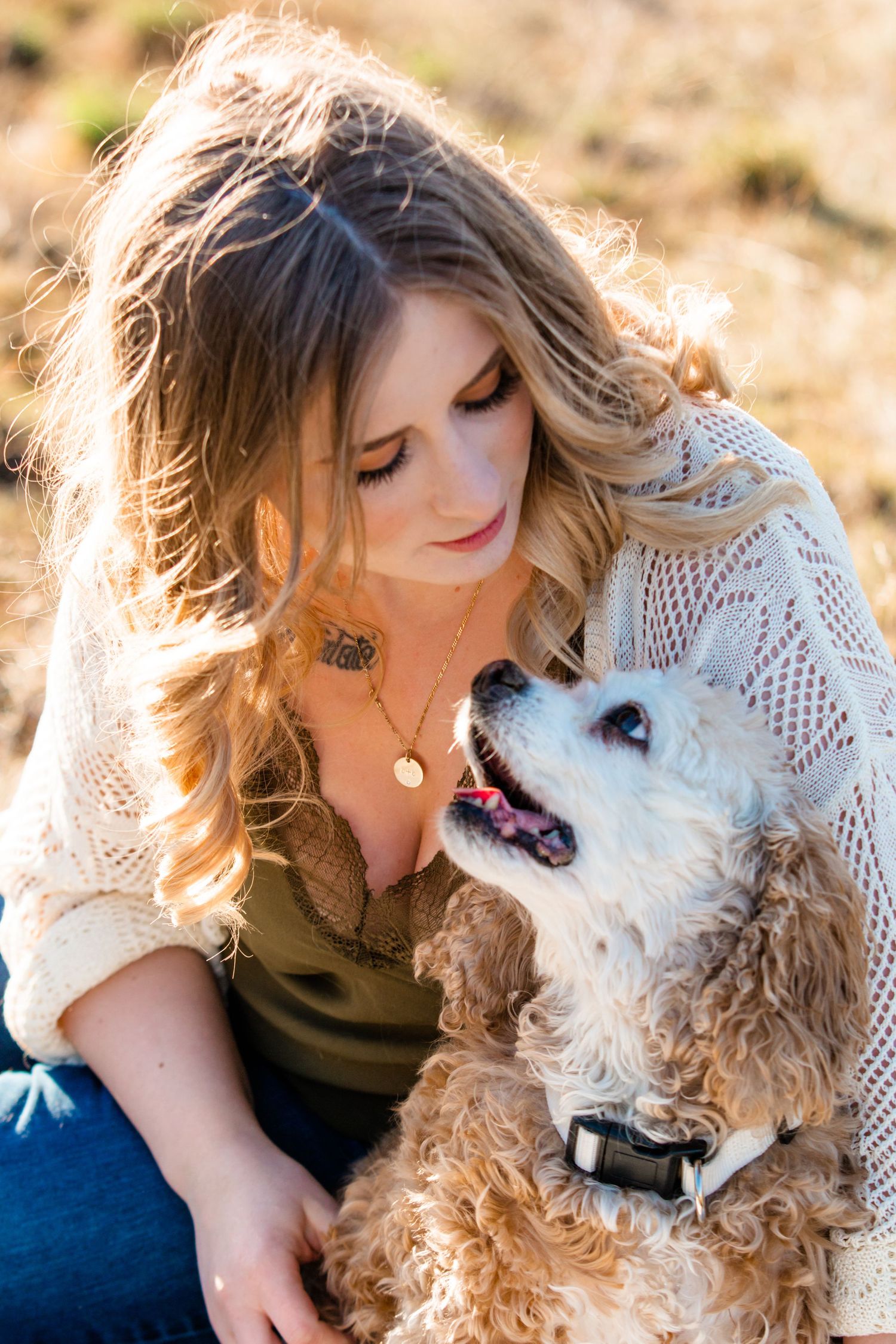 Woman in white lace cuddling with fluffy white dog outdoors.