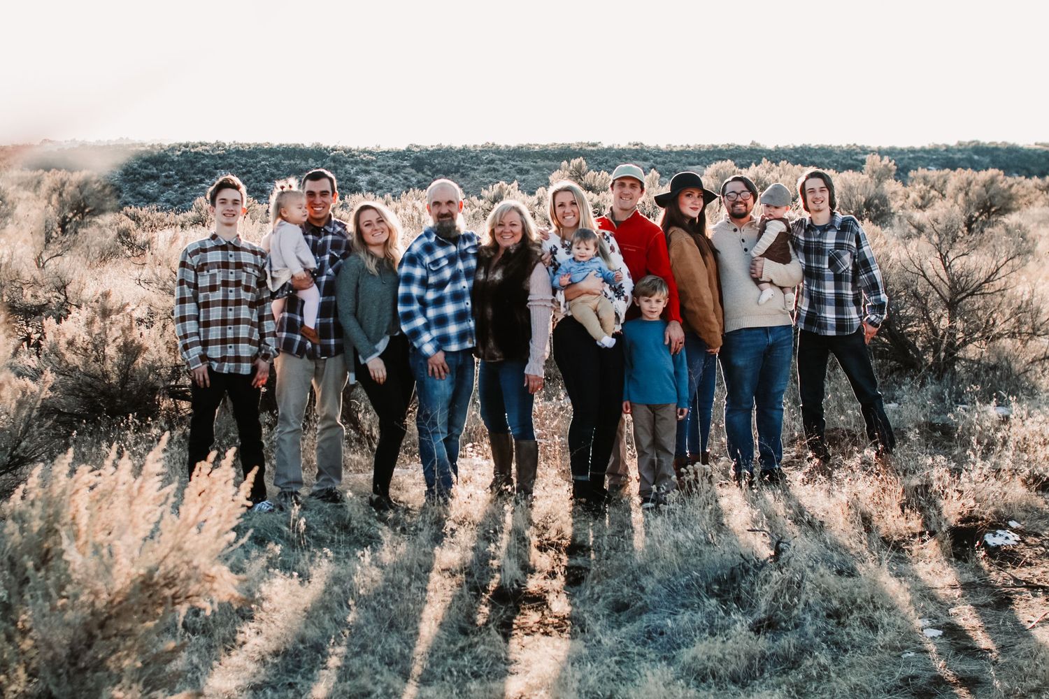 Group of people standing together on a hillside at sunset.