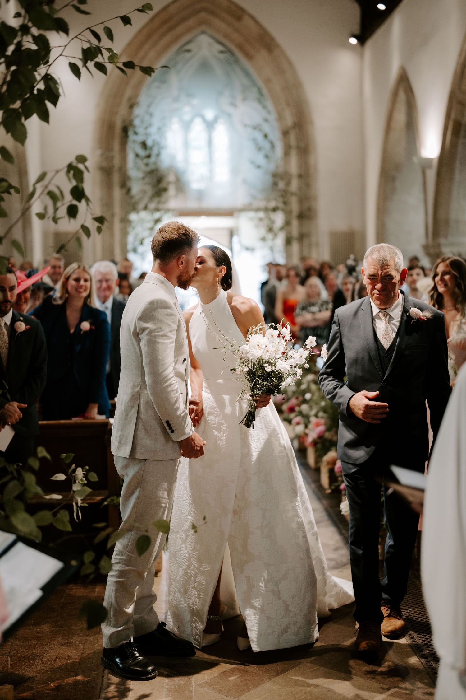 bride and groom sharing a kiss at the alter at st Nicholas church in Oxfordshire