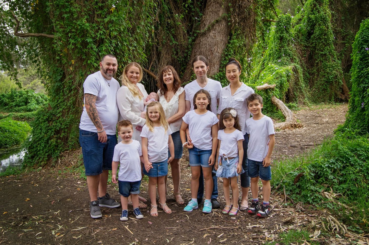 Family portrait outside witih adults and children dressed in white and blue smiling at camera