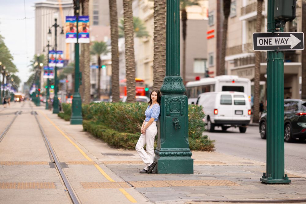 Urban street scene with palm trees and green lamp posts along trolley tracks.