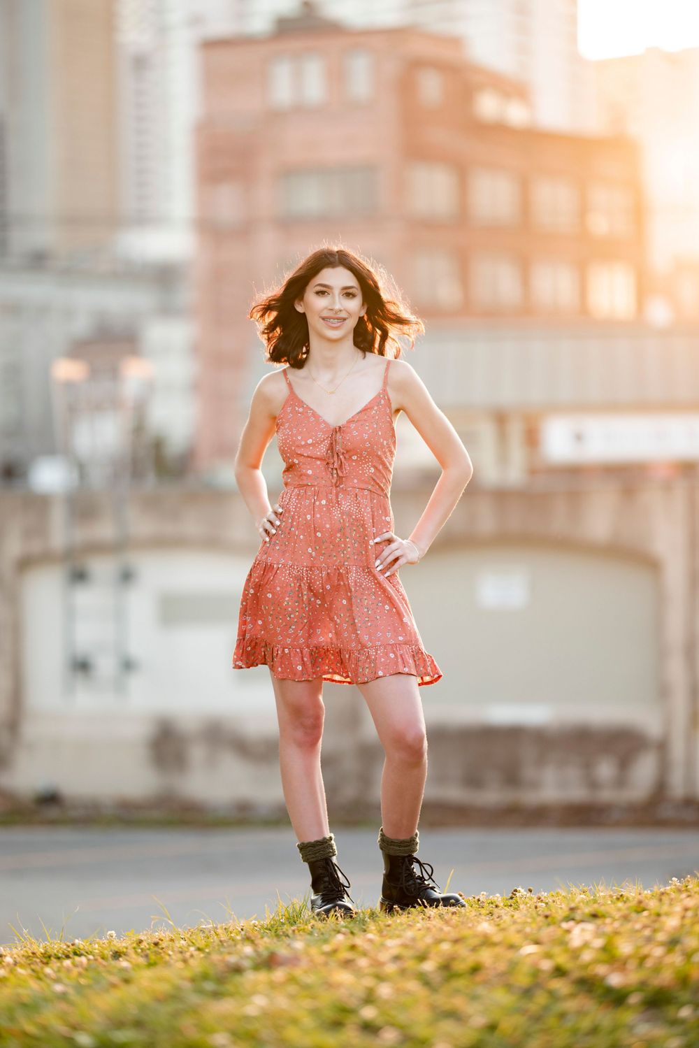 A flowy coral dress catches sunlight during a golden hour photoshoot in an urban setting.