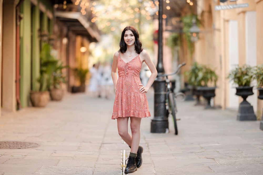 A coral summer dress paired with boots creates a stylish urban look on a charming street.