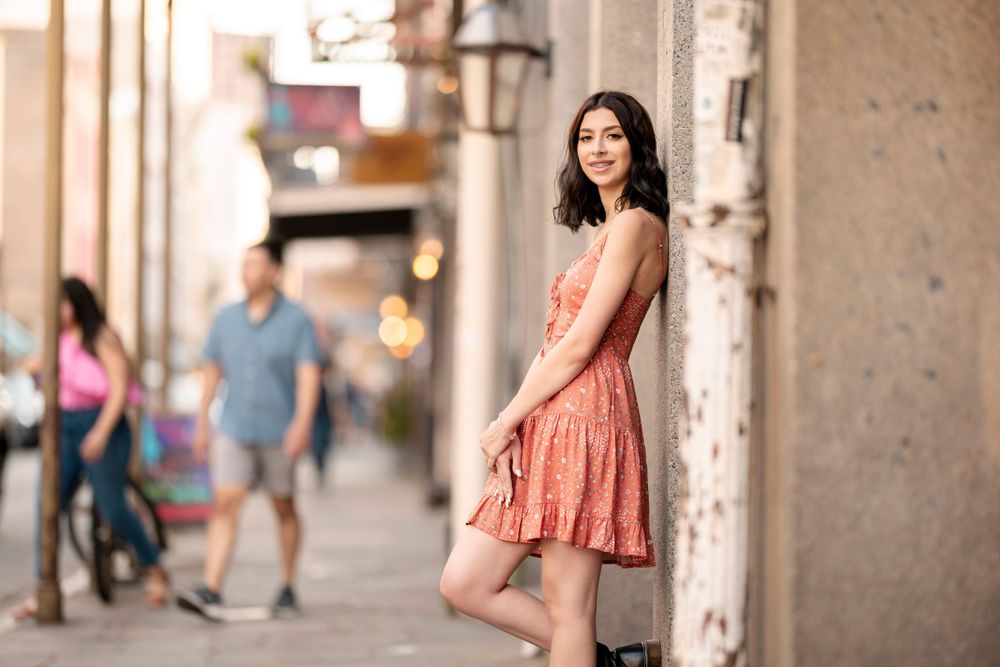 A flowing coral dress creates an elegant silhouette against historic architecture and streetlamps.