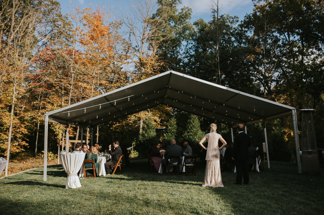 An outdoor wedding venue with a covered pavilion surrounded by autumn trees.