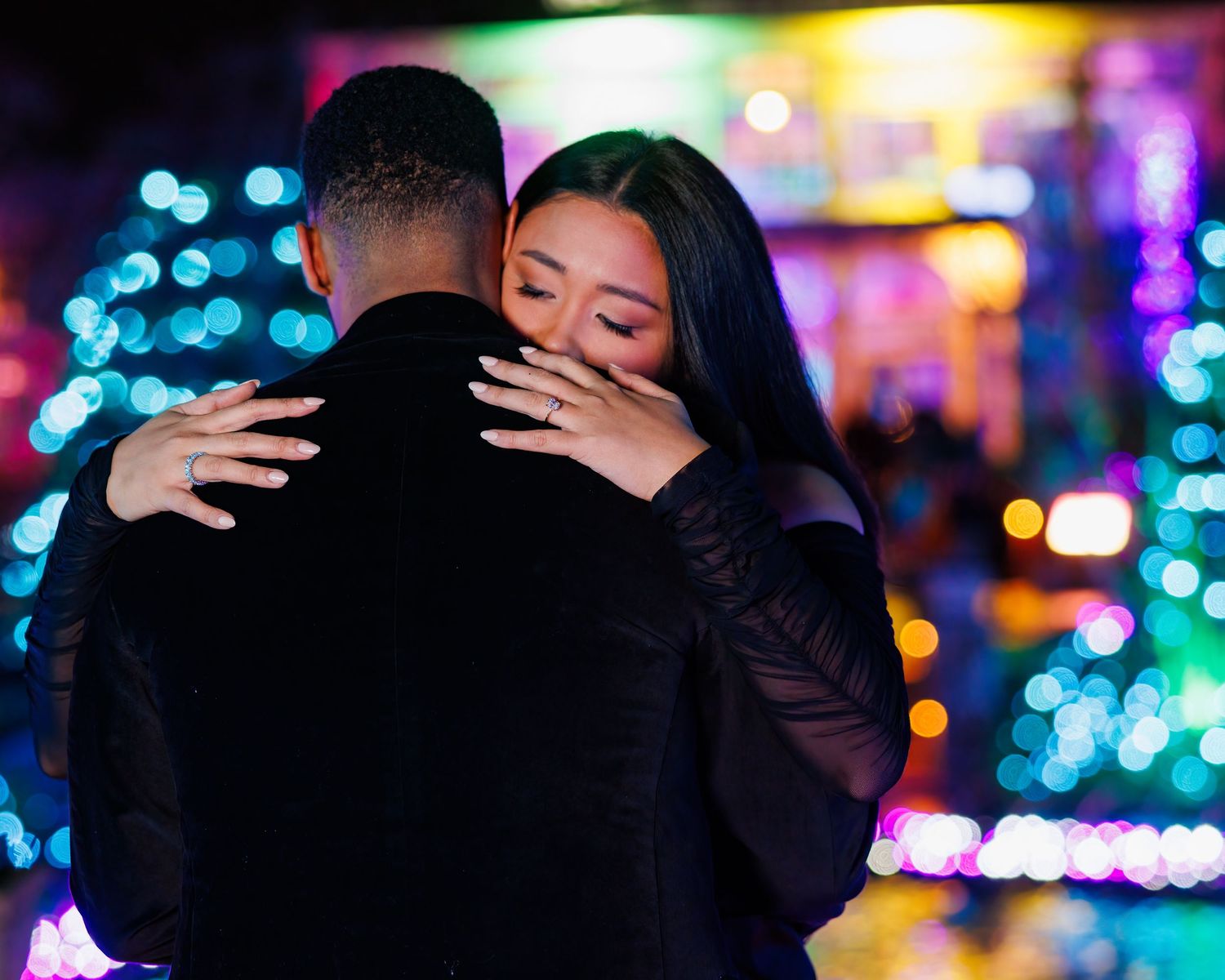 Couple embracing with bokeh lights in the background of various colors at Lewis Ginter