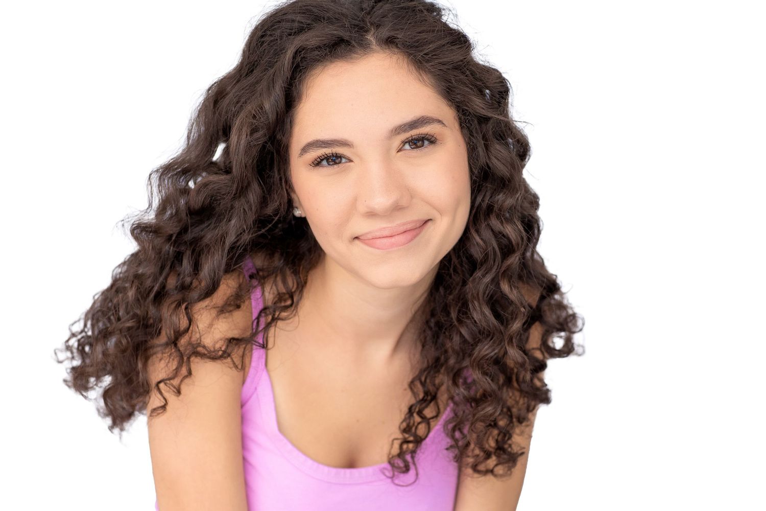 Studio portrait with natural curly hair wearing pink tank top against white background.