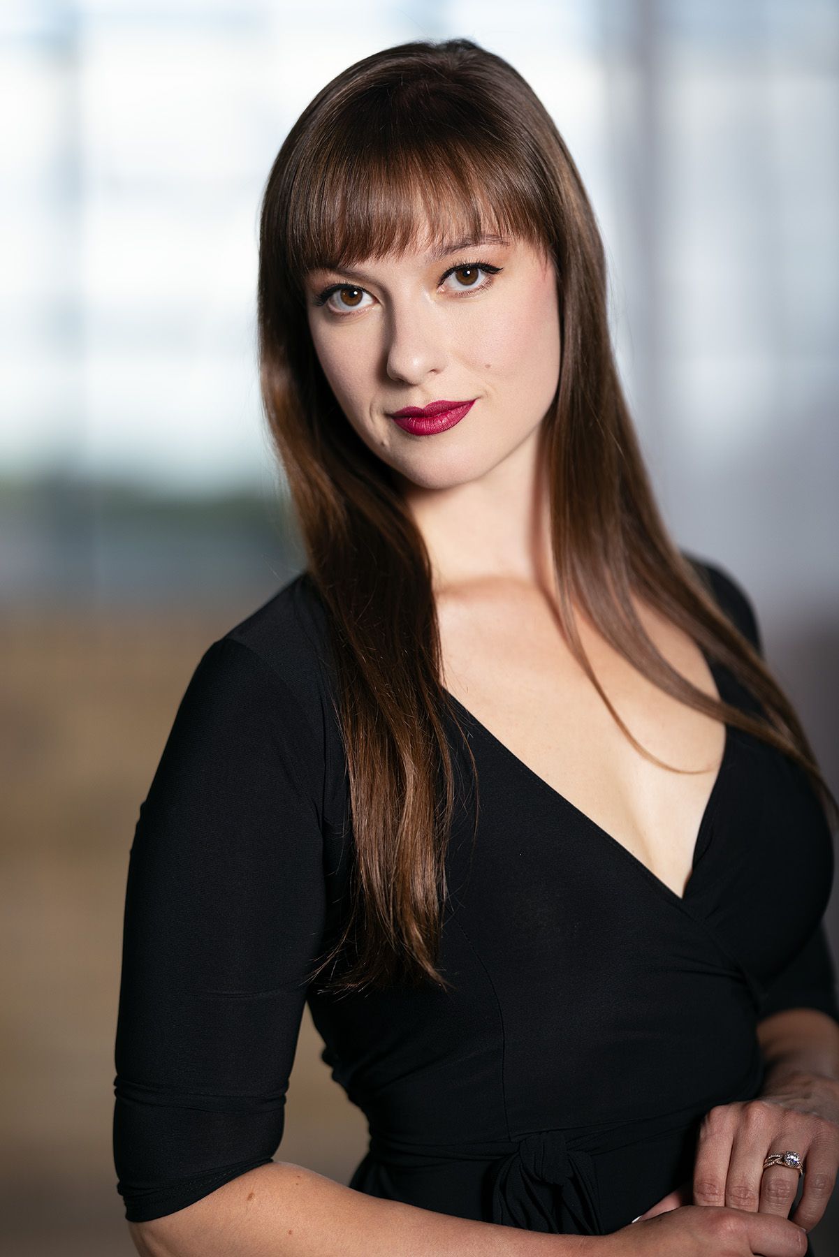 Professional studio portrait of a woman with long brown hair wearing a black v-neck dress. Photographer Gerardo Dominguez