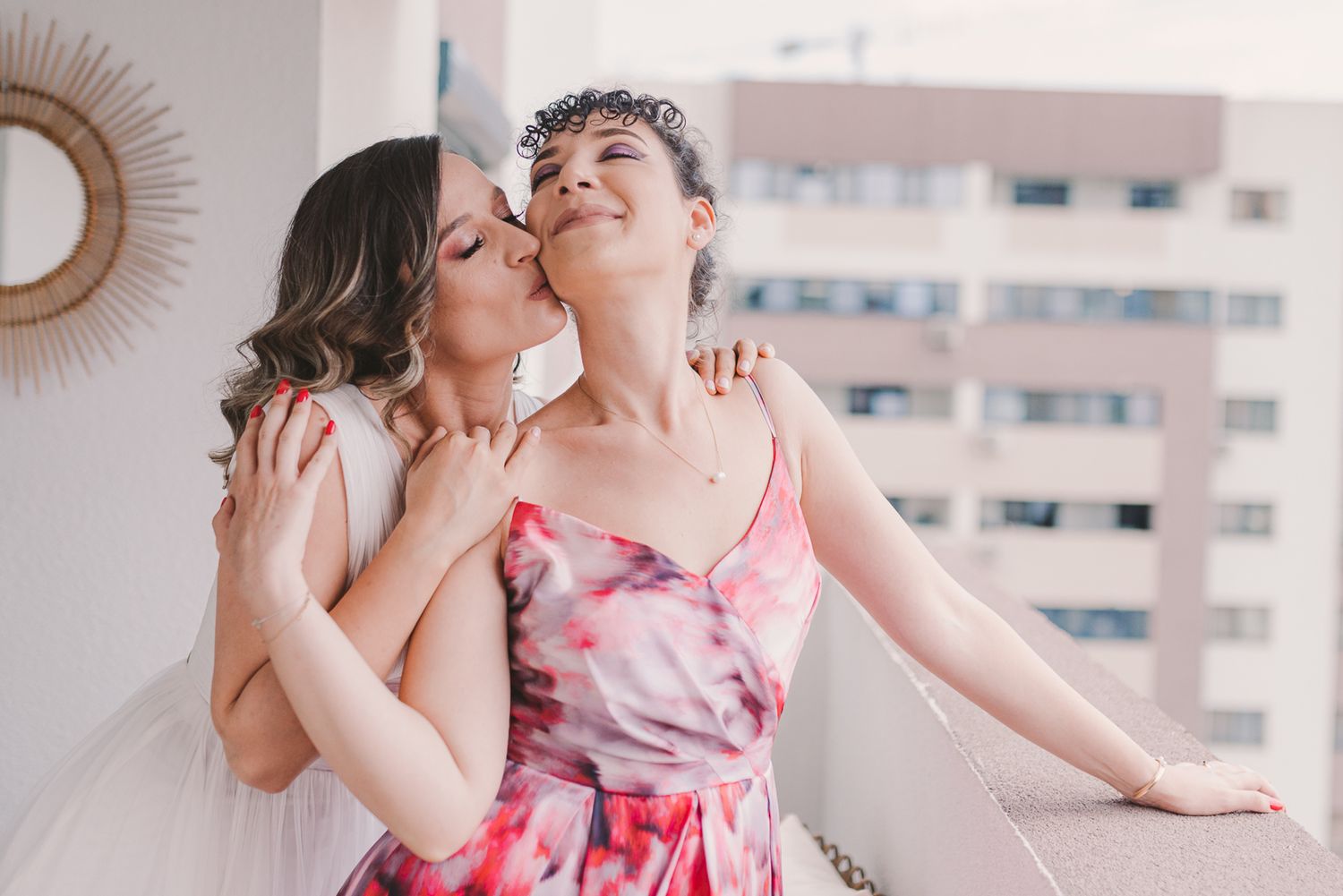 Friends pose playfully against a bright wall with a sunburst mirror decoration.