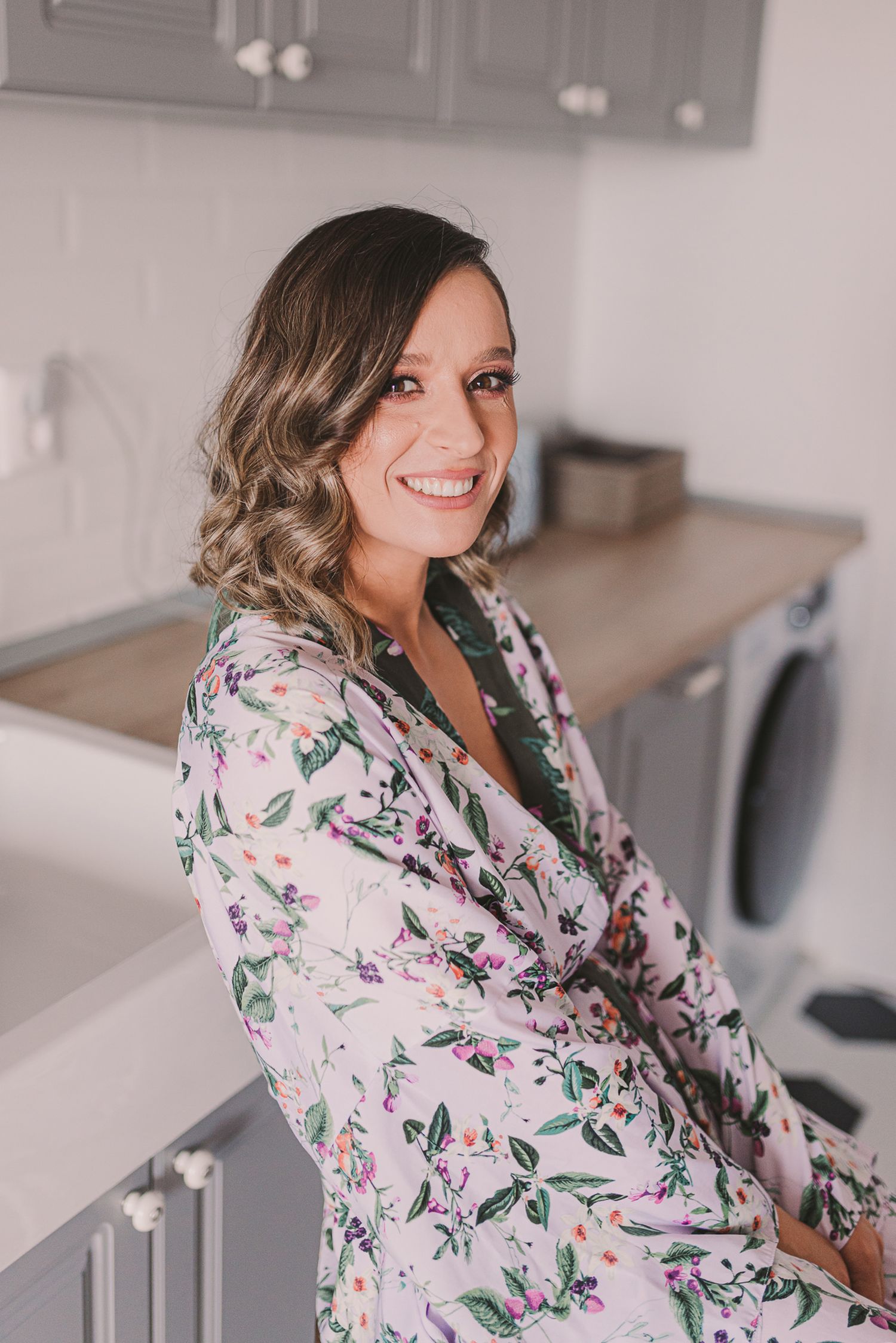 Woman in floral print robe posing in modern interior setting.