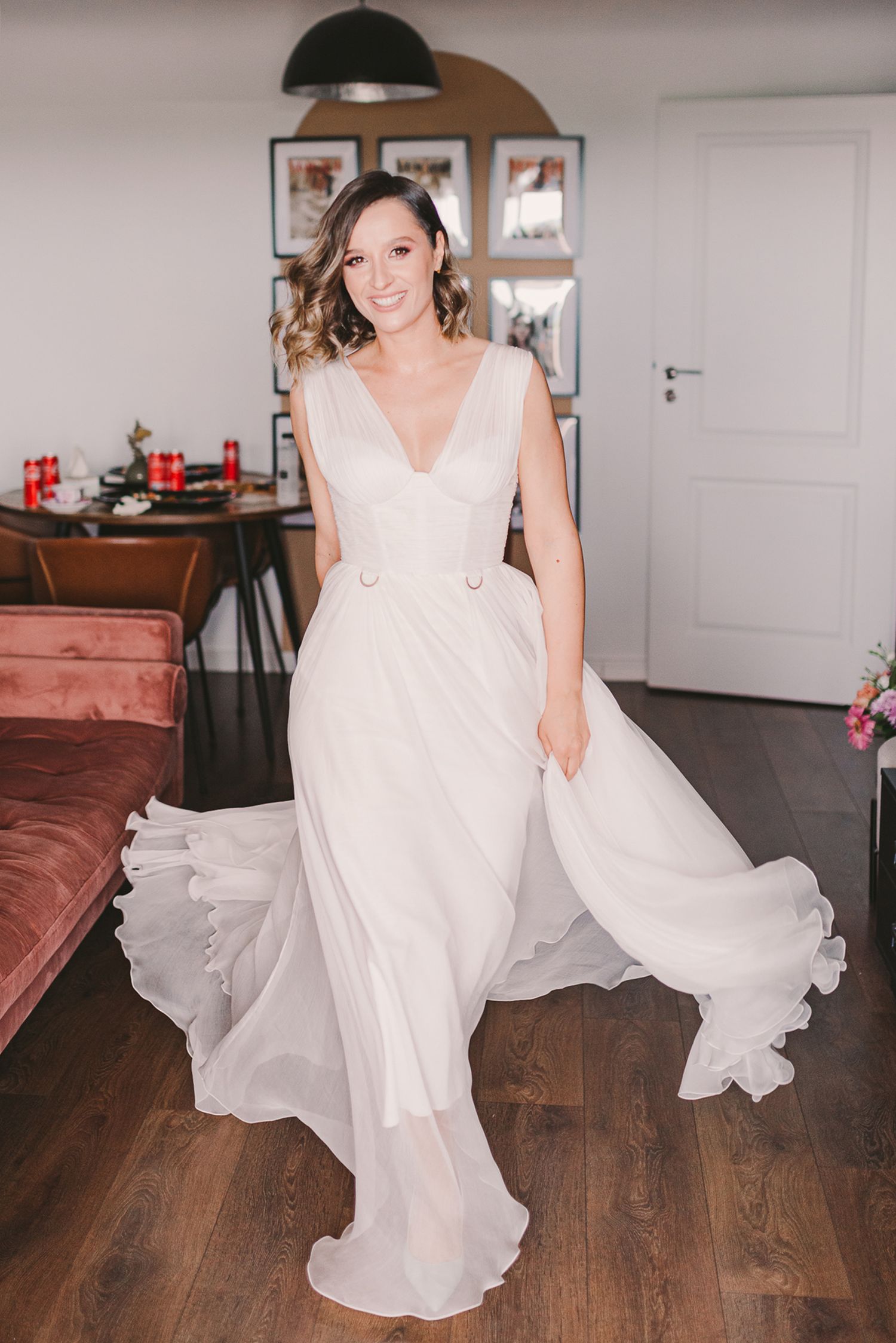 Woman in flowing white dress twirling on hardwood floors indoors.