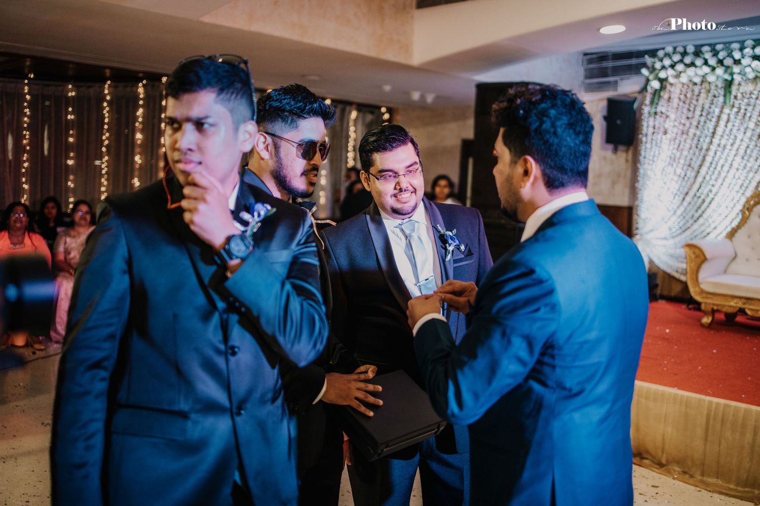 Groomsmen in blue suits having an animated conversation at a wedding reception.