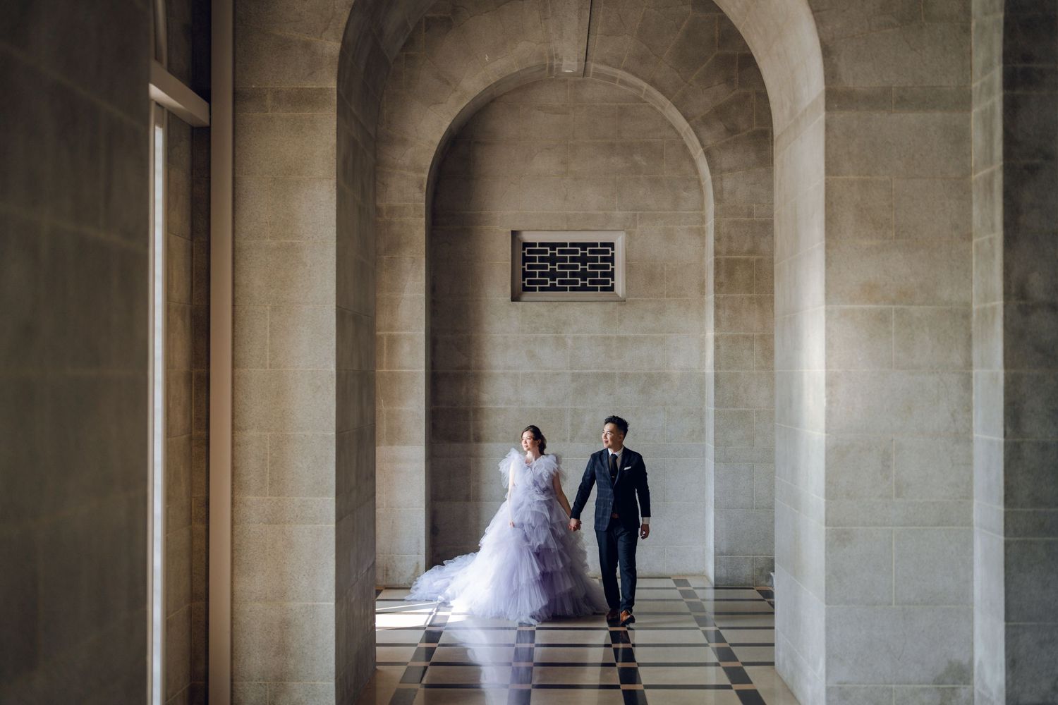Wedding photoshoot in a grand stone colonnade with dramatic lighting and architecture.