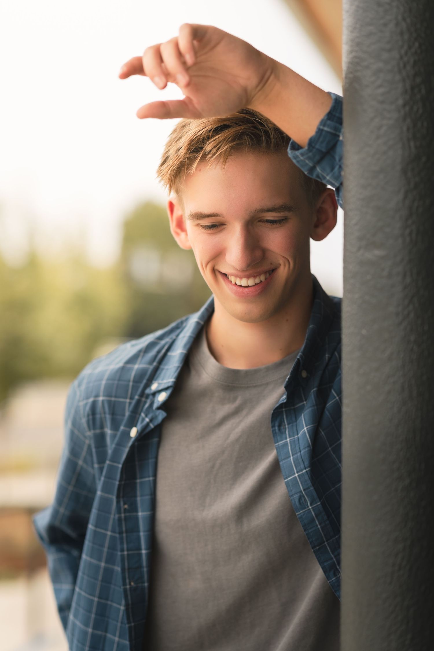 Senior with arm resting on pole above head looking down and smiling