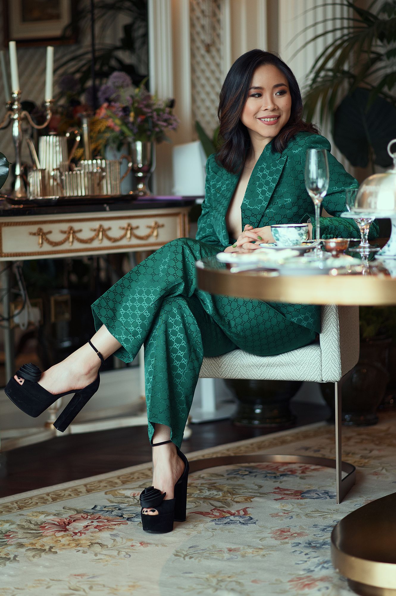 Nga Nguyen photoshoot in London. She is wearing a green Gucci outfit smiling around the dinning table in the Gucci room