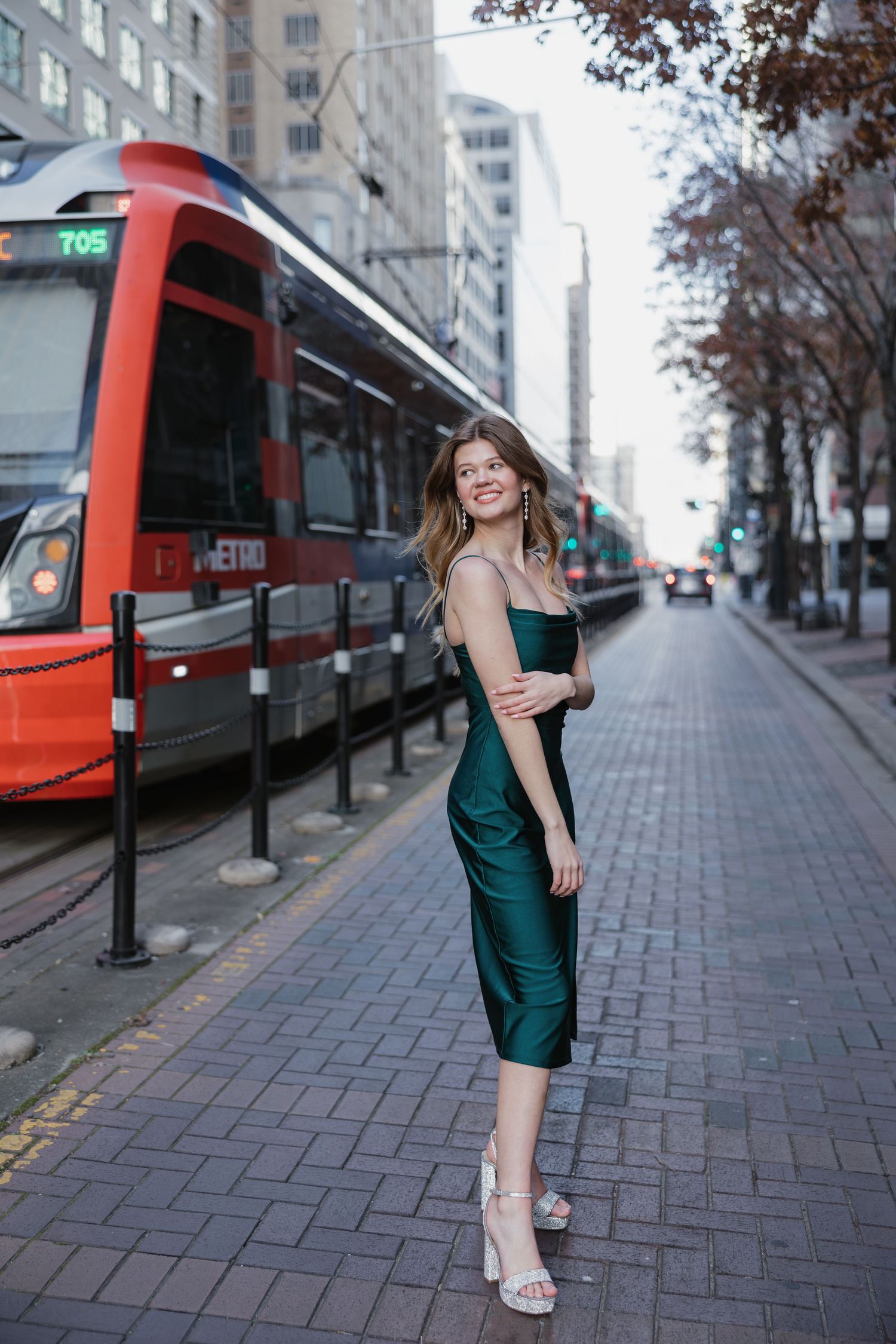 Street fashion portrait with red transit tram featuring person in emerald green dress.